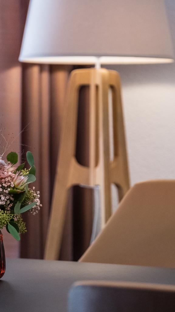 Tisch mit Blumenstrauss im Hintergrund eine Ständerlampe